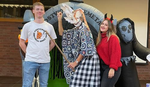 Drei Personen in Halloweenoutfits vor einer Halloweendekoration